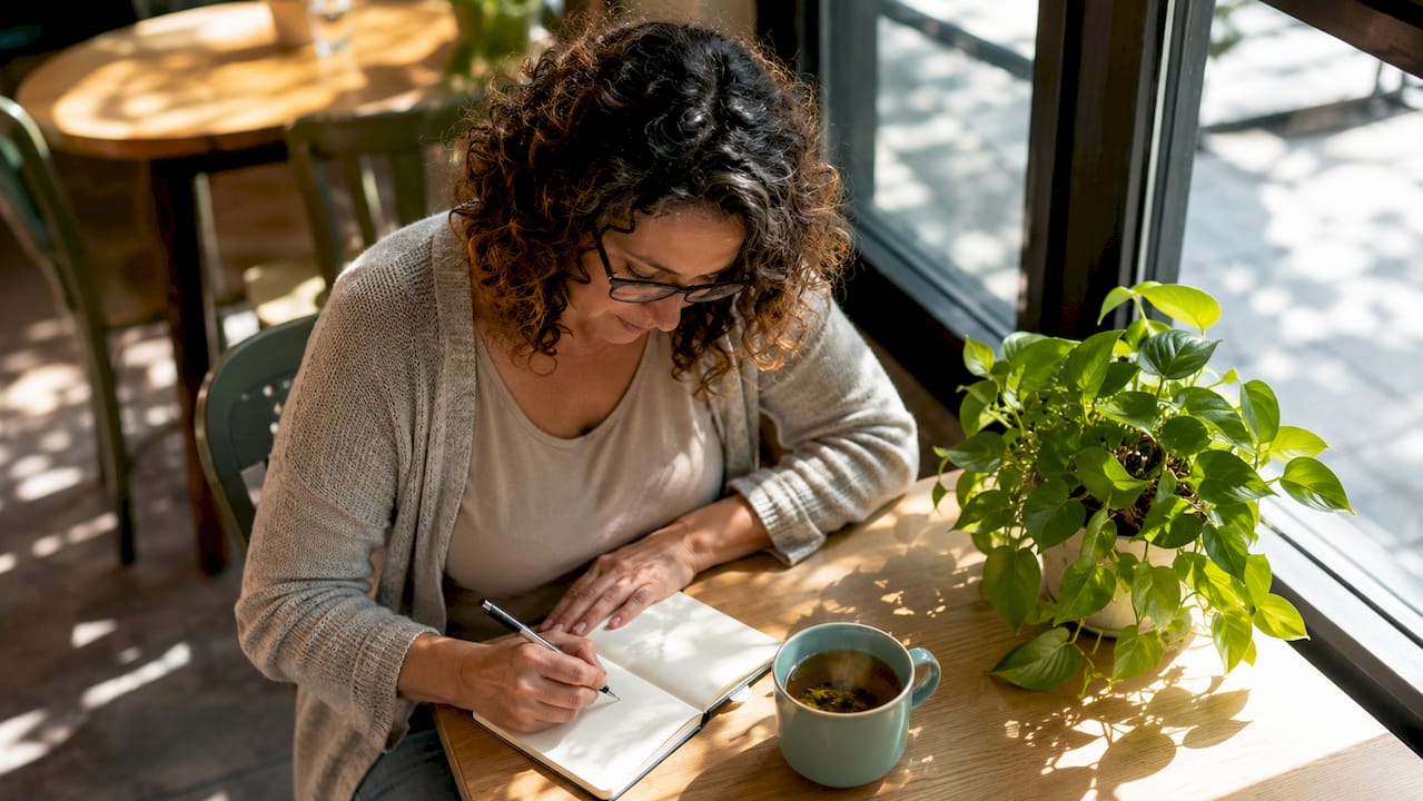 Woman planning self-care habits at kitchen table