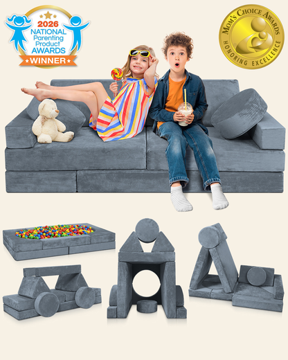 Gray modular foam play couch with children sitting on it, plus several toy play blocks and a ball pit shown below on a light beige background. Awards badges appear in the corners.