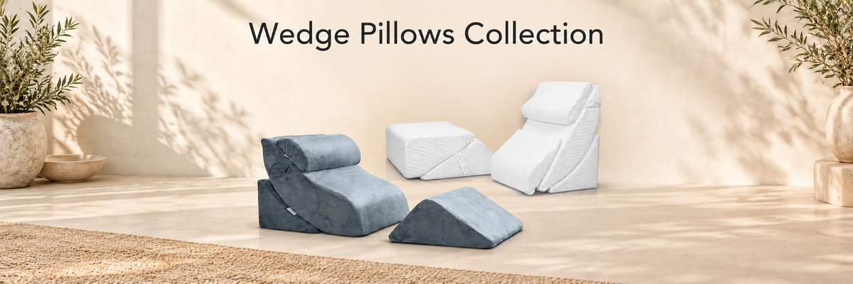 Four Lunix wedge pillows displayed in a warm, sunlit room setting. The collection includes two navy blue pillows (one contoured, one flat triangular) and two white pillows (one rectangular block and one wedge chair).